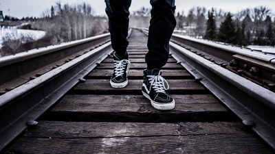 人穿着一双黑白货车老布朗茱莉安鞋走在铁轨在冬天

